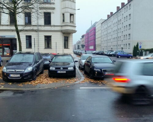 Auto fährt an parkenden Autos vorbei