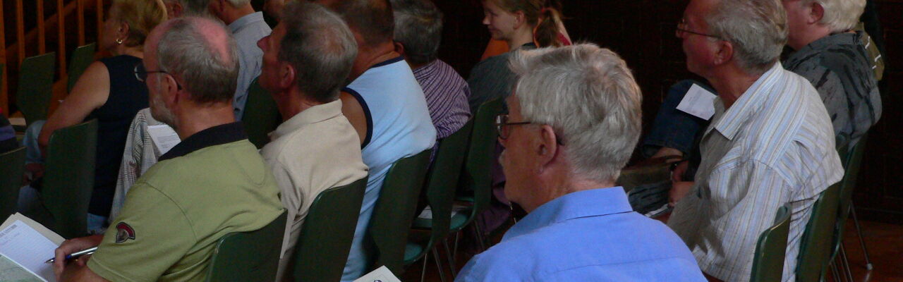 Menschen sitzen vor einer Leinwand und hören einem Vortrag zu