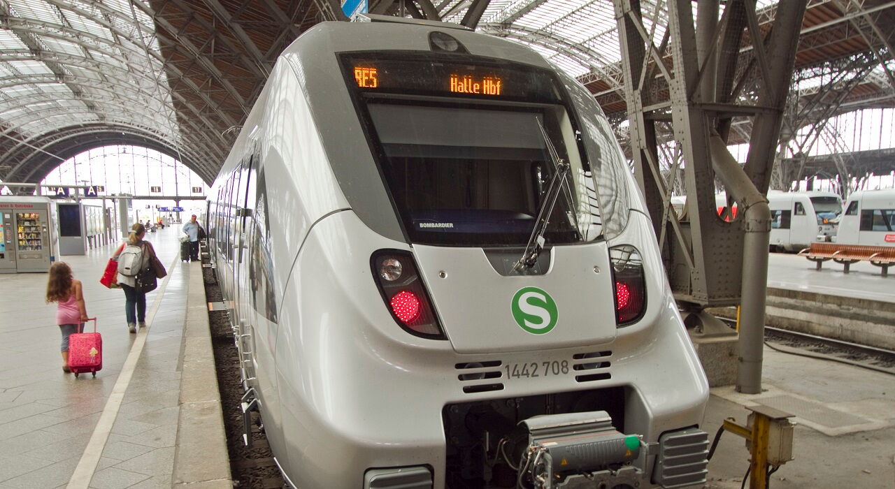 S-Bahn am Bahnsteig im Hauptbahnhof Leipzig . Daneben Fahrgäste mit Koffern, die zum Zug gehen.