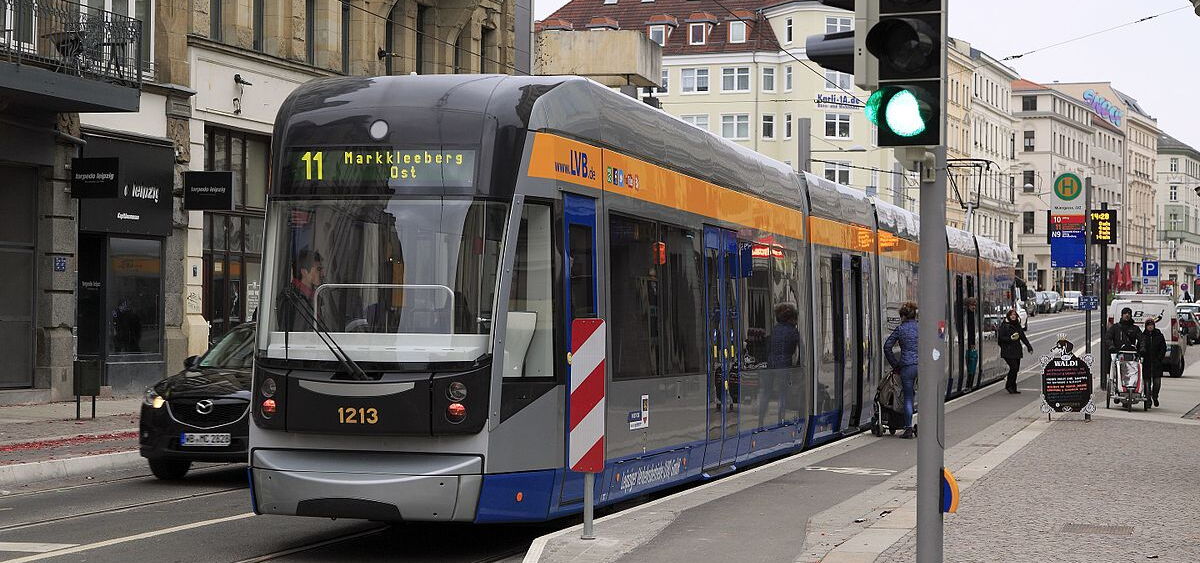 Straßenbahn an einer Haltestelle mit Fußgängern