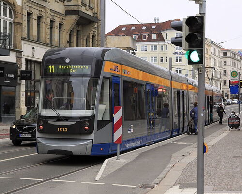 Straßenbahn an einer Haltestelle mit Fußgängern