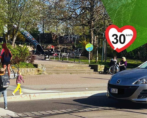Im Hintergrund ist ein Spielplatz in Leipzig mit Rutsche zu sehen. Im Vordergrund gehen zwei Kinder über die Straße. Davor hält ein Auto. Ein Tempo 30 Schild in Herzform ist auf das Bild gedruckt
