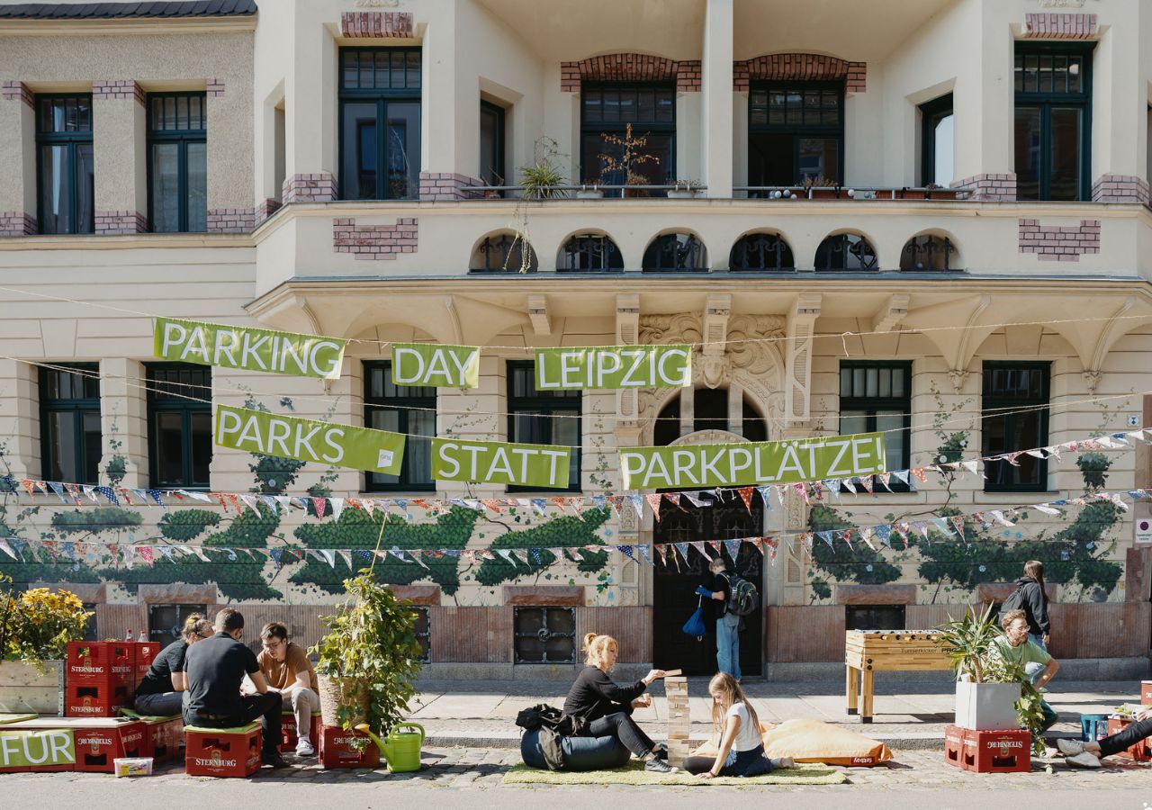 Gemeinsam gestalten Menschen während des Park(ing) Day eine Parklücke zu einem kleinen Park um.