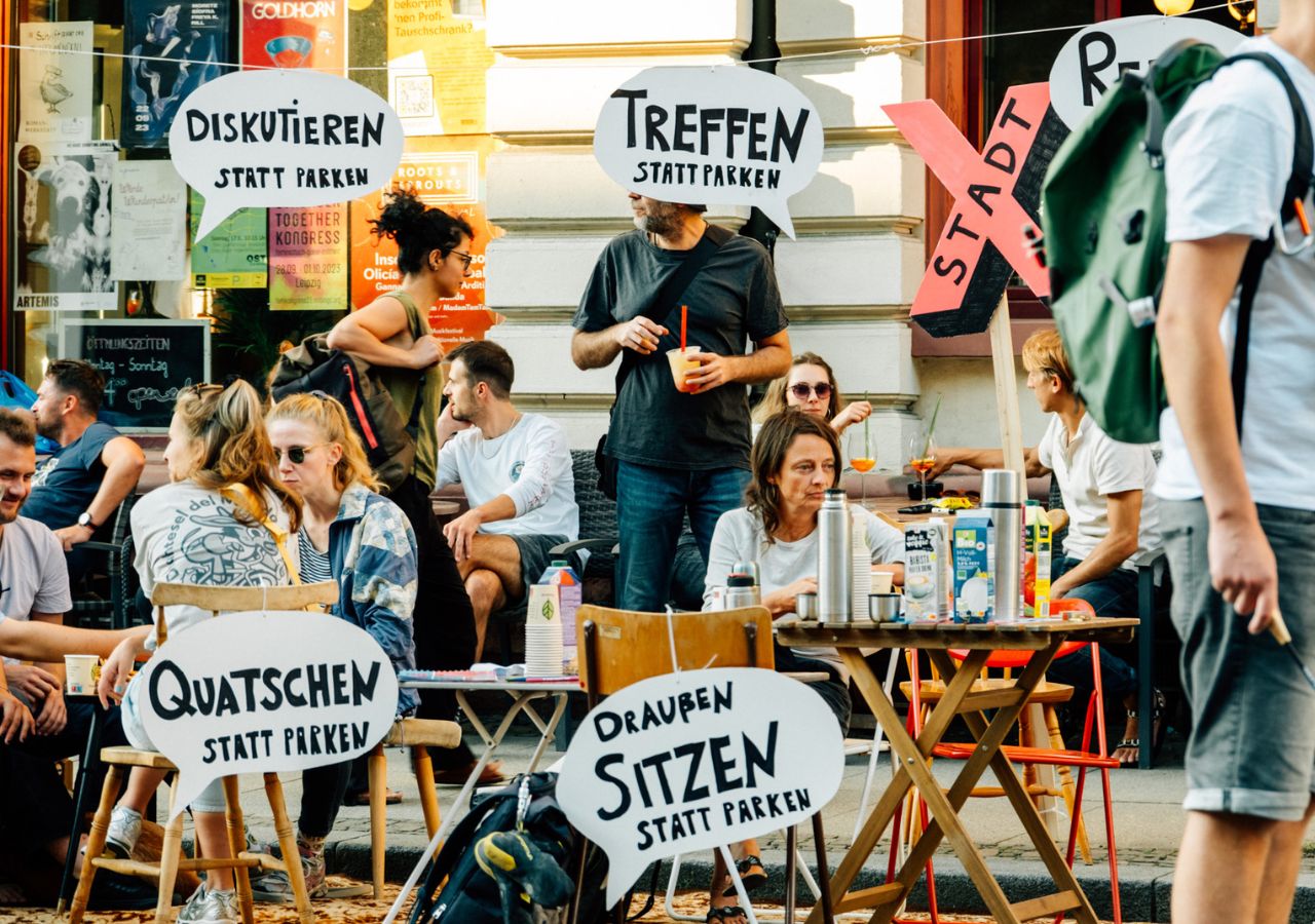 Gemeinsam gestalten Menschen während des Park(ing) Day eine Parklücke zu einem kleinen Park um.