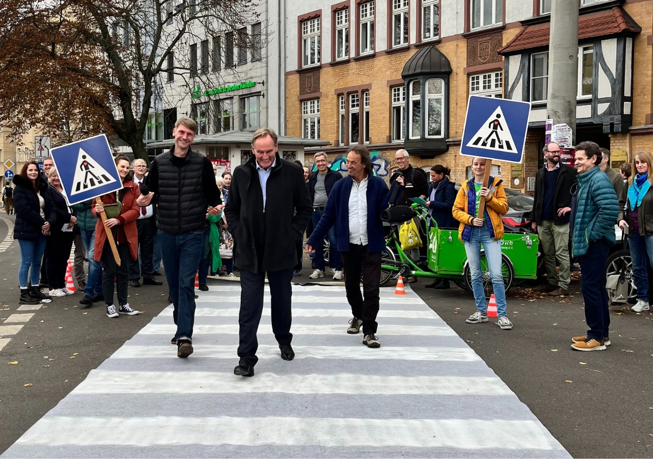 Gruppe von Personen überquert Zebrastreifen mit Fußgängerschildern.
