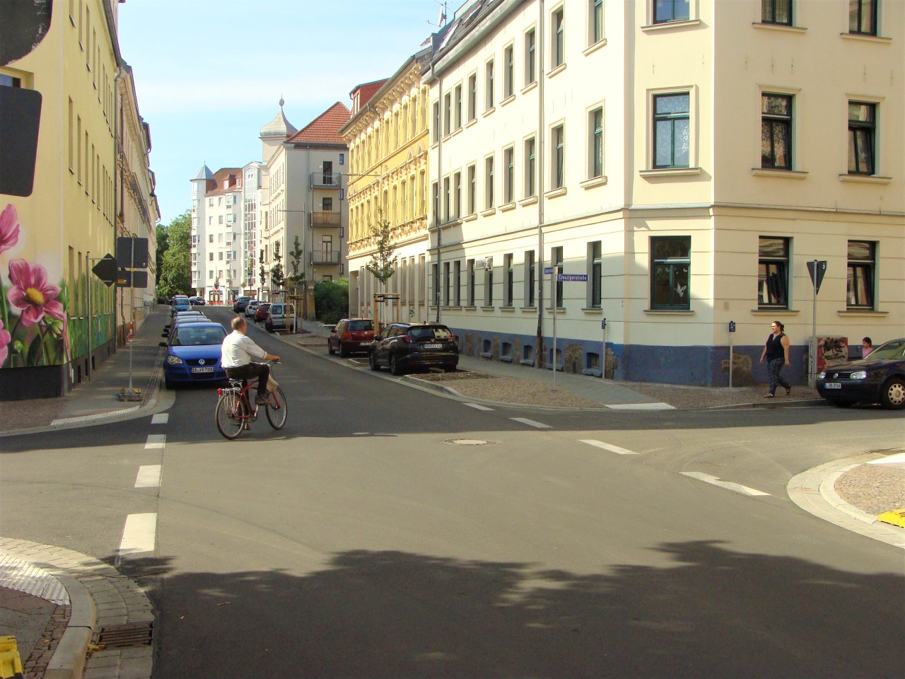 sanierter Kreuzungsbereich Creuzigerstraße und Gießerstraße. Ein Radfahrer biegt ab. Mutter und Kind wollen die Straße überqueren.