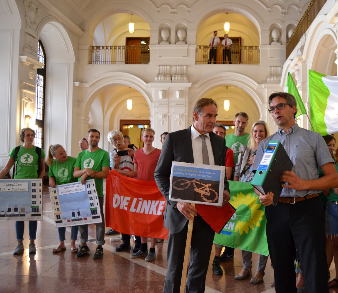 Gruppe von Menschen mit Ökolöwen-Shirts, Schildern, Flaggen von Die Linke und Grünen mit dem Oberbürgermeister Jung, der ein Schild hält, in der Wandelhalle im Neuen Rathaus