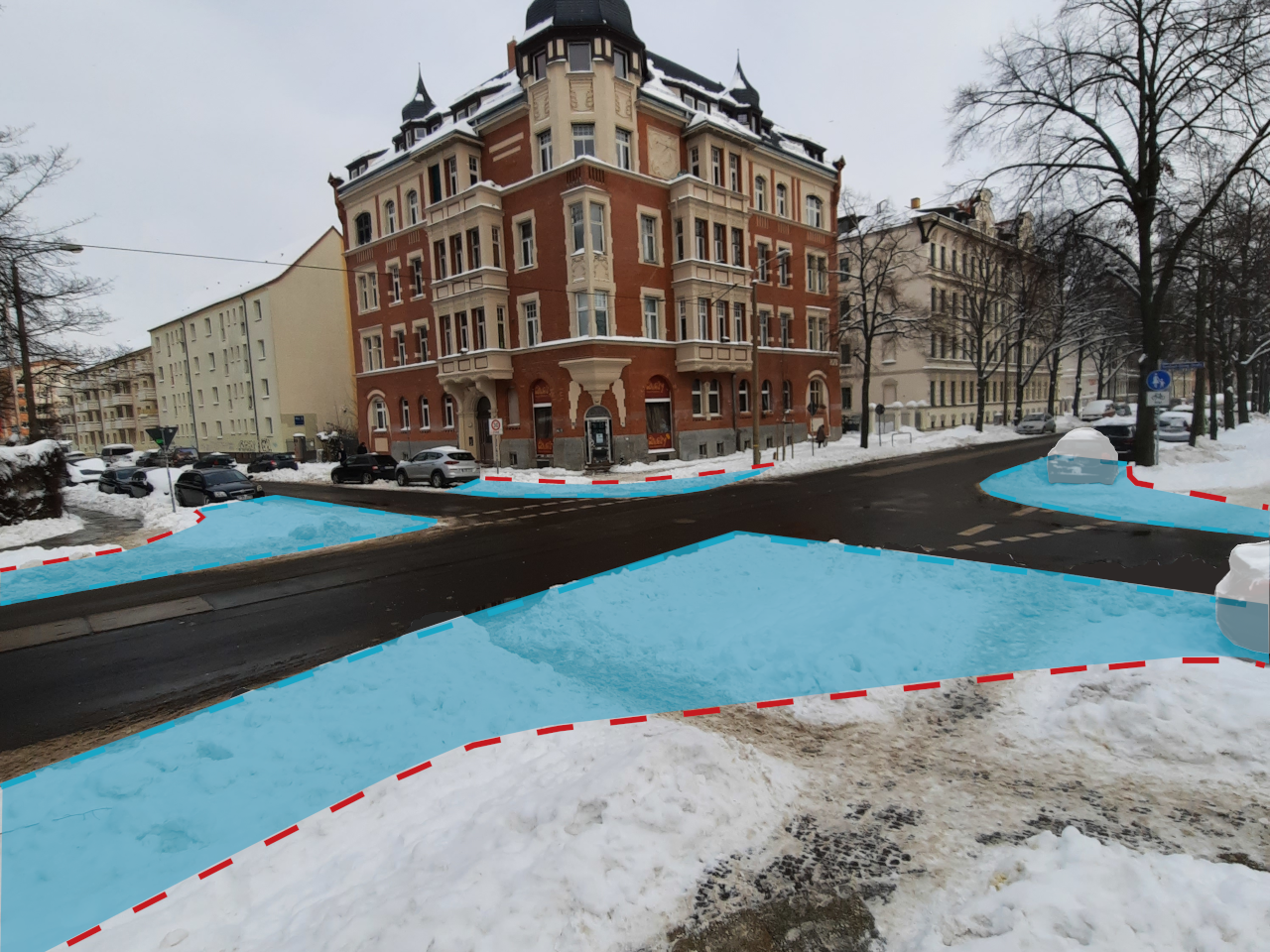 Sneckdown-Foto von der Arno-Nitzsche-Straße im Winter. Die blauen Schnee-Flächen der Straßenkreuzung können sofort den Fußgänger:innen zurückgegeben werden. Die rote Strichellinie markiert den aktuellen Bordstein.