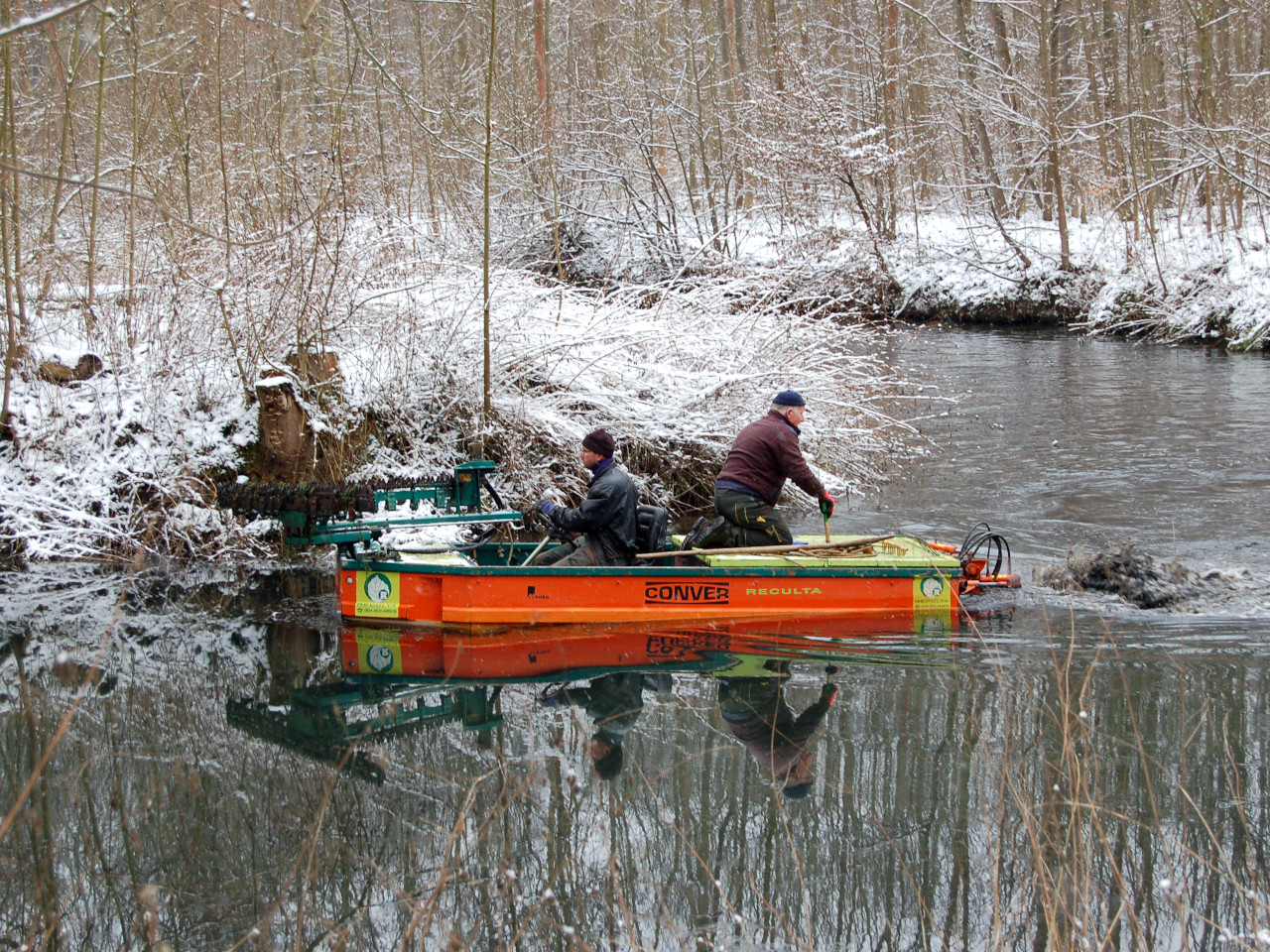 Zwei Männer in einem Motorboot entkrauten den Floßgraben